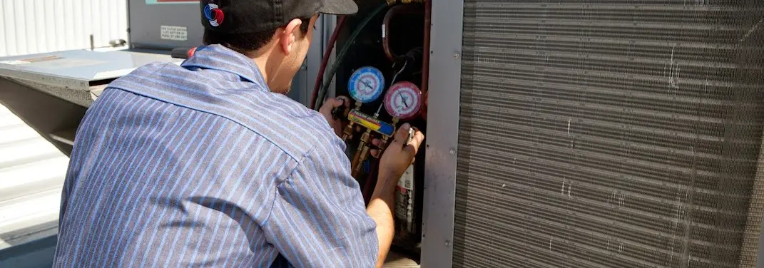 HVAC technician servicing a condenser unit in Dunbar